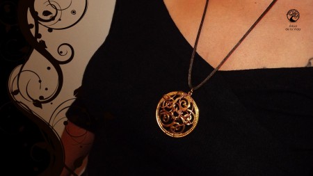 jhenna  Collana di media lunghezza con cordoncino in coda di topo marrone/verde, ciondolo color oro sul quale si arrampica l'albero della vita realizzato a mano con filo in rame, i rami ed il tronco si intersecano con il disegno del medaglione creando int